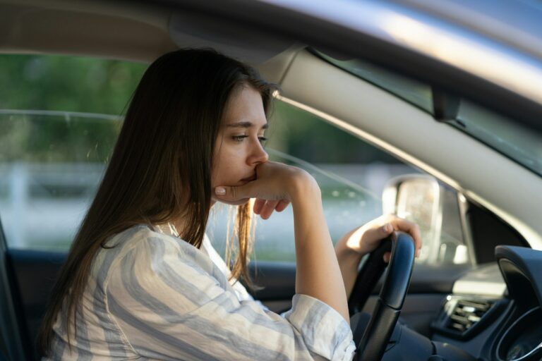 Drunk girl driving car. Unhappy tired young female in vehicle suffering from headache or handover