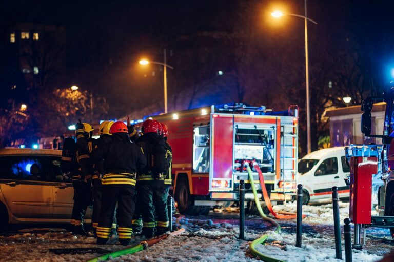 Firemen at work near their truck on the street.