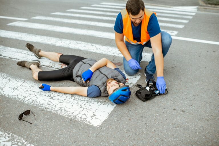 Road accident with injured cyclist and man providing first aid