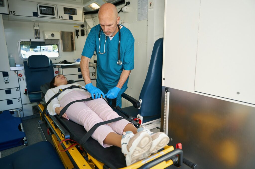 Doctor tightens seat belts on body of patient in ambulance