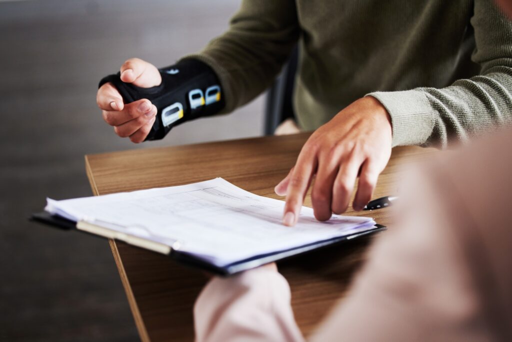a person with a wrist brace pointing at a piece of paper
