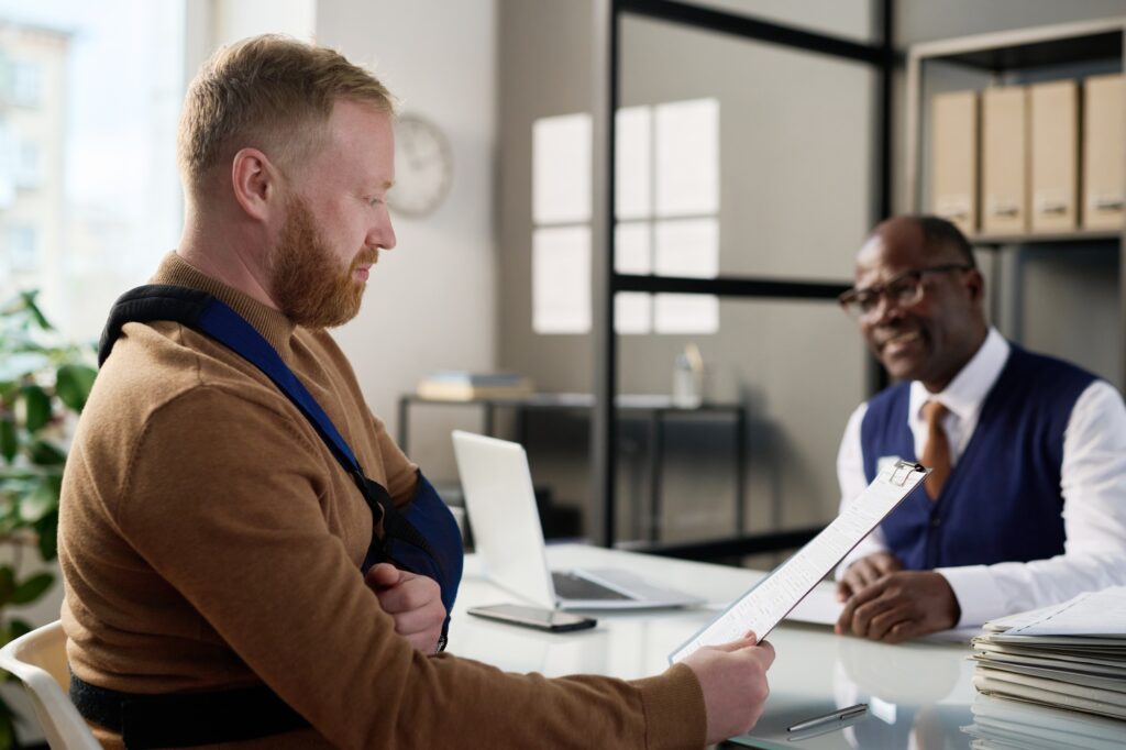 a man with a sling on his arm looking at a clipboard