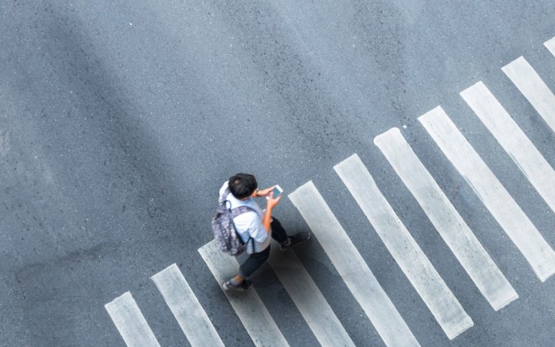 man walking in a crosswalk on his phone