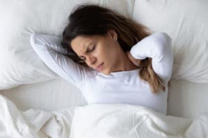 woman clutching neck in bed