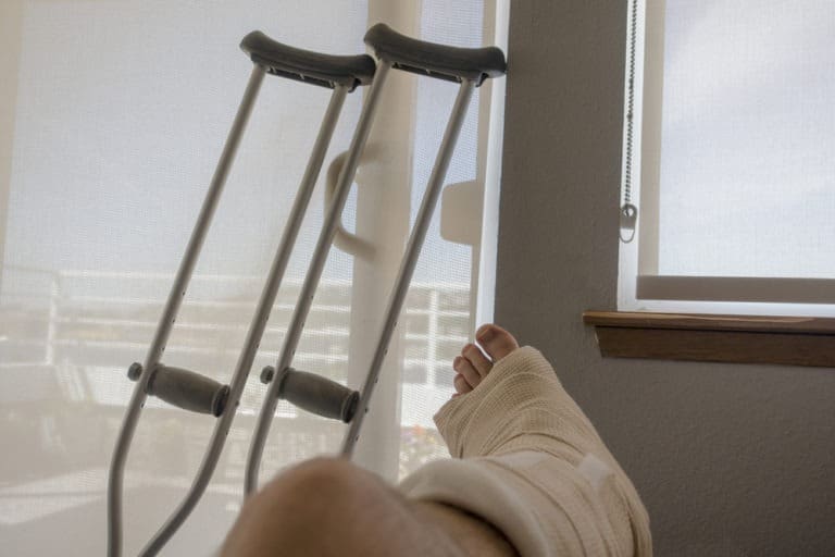 close-up of person’s leg in a cast with crutches