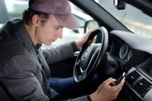 man driving car while checking his cell
