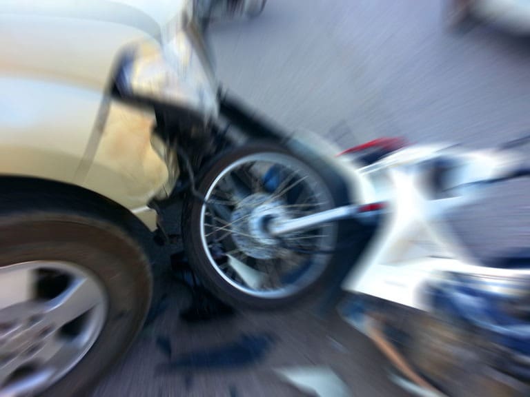 motorcycle crashing into a tan car