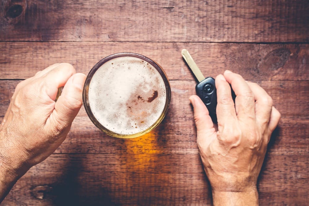 a driver holding a beer mug and car key