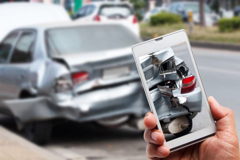 hand holding phone takes picture of vehicle damage