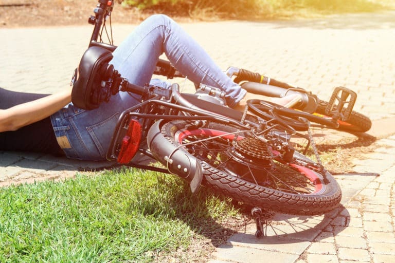 person lying on the road under her bike