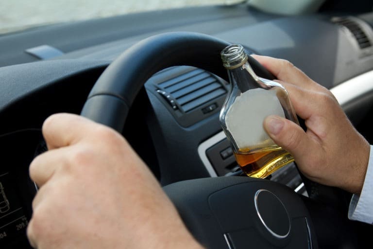 person holding alcohol while driving
