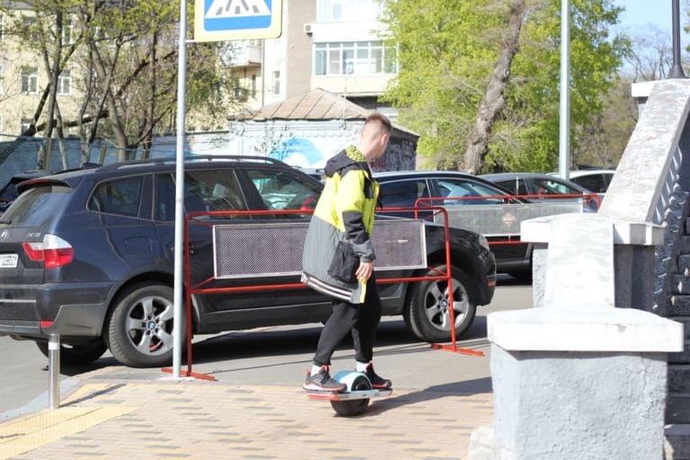 young adult riding a Onewheel on an urban sidewalk