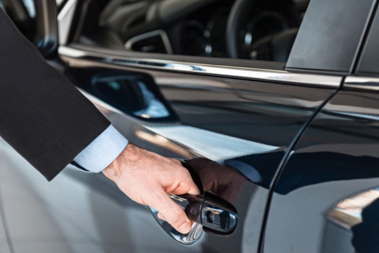 man reaching for the handle of a company car