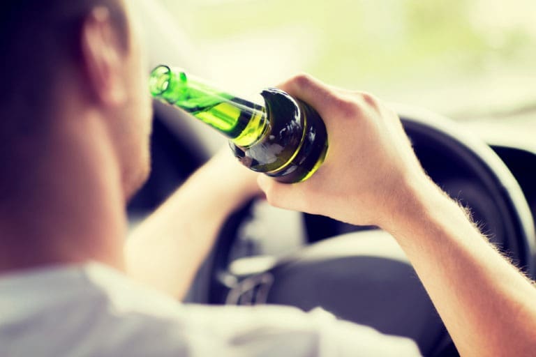 a-man-drinking-from-a-beer-bottle-while-driving
