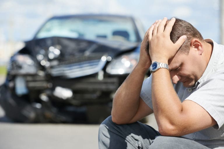 man-holds-head-after-drunk-driving-car-accident
