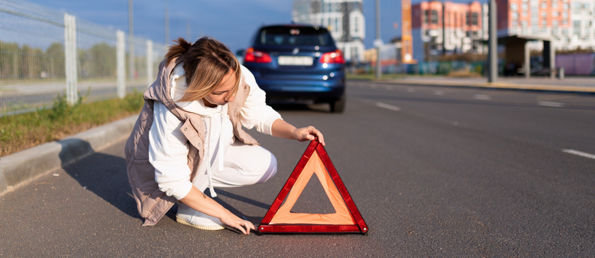a woman driver puts an emergency stop sign near a broken car, traffic accident concept
