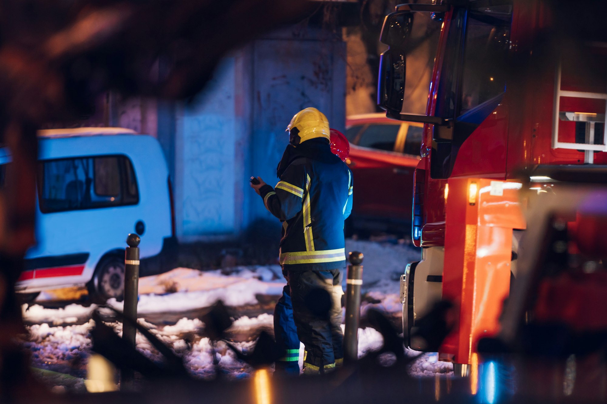 Firemen at work near their truck on the street.