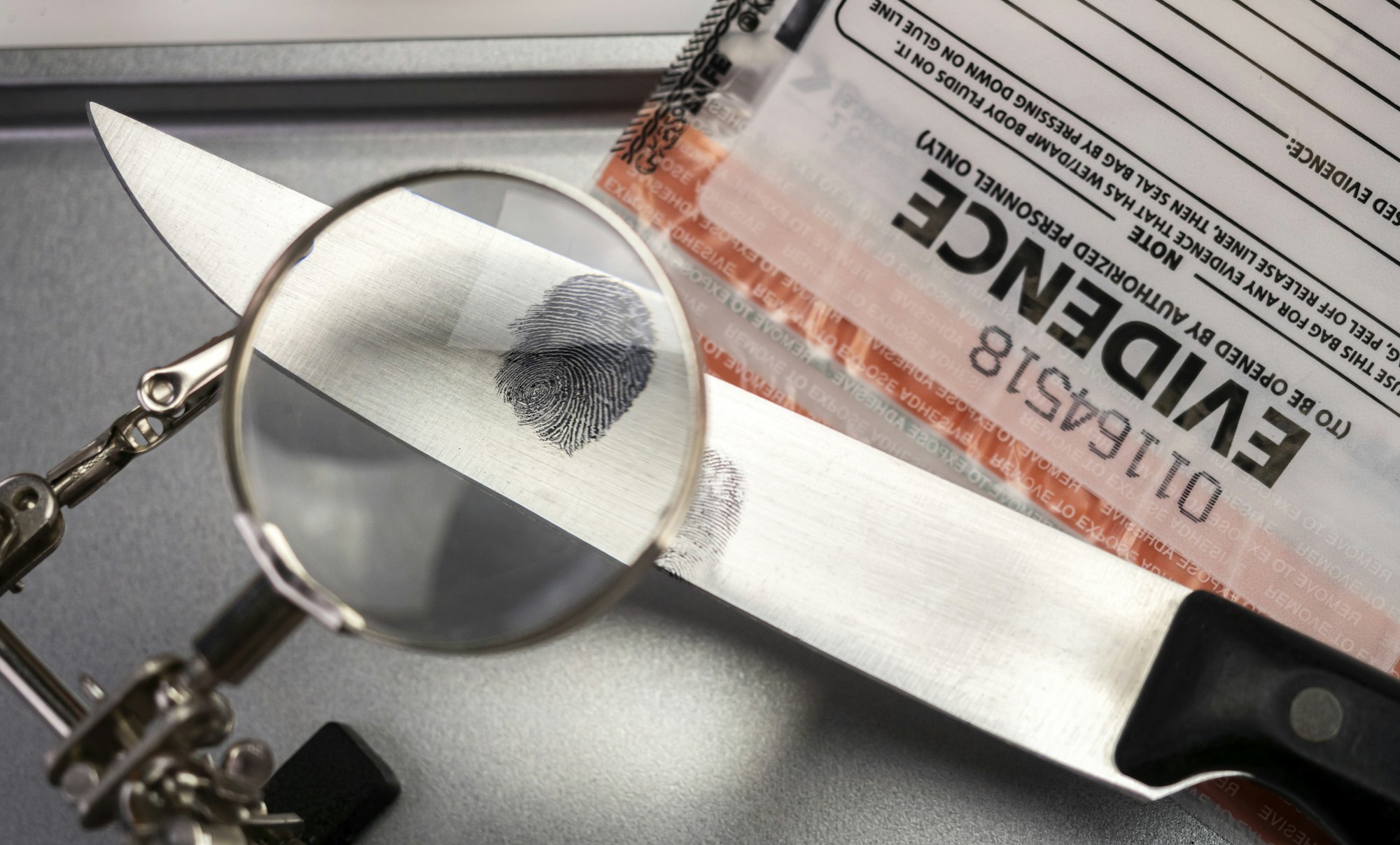 Police investigation of fingerprint on a knife, concept image