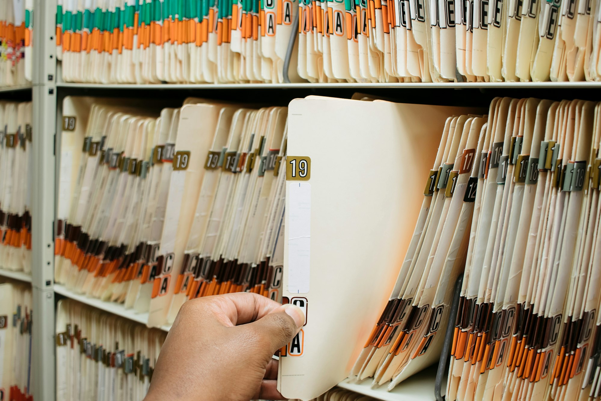 African American man pulling medical records, charts, from pile