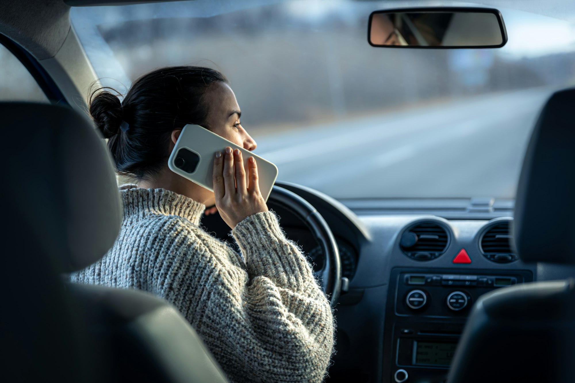 Young woman talking on the phone while driving a car.