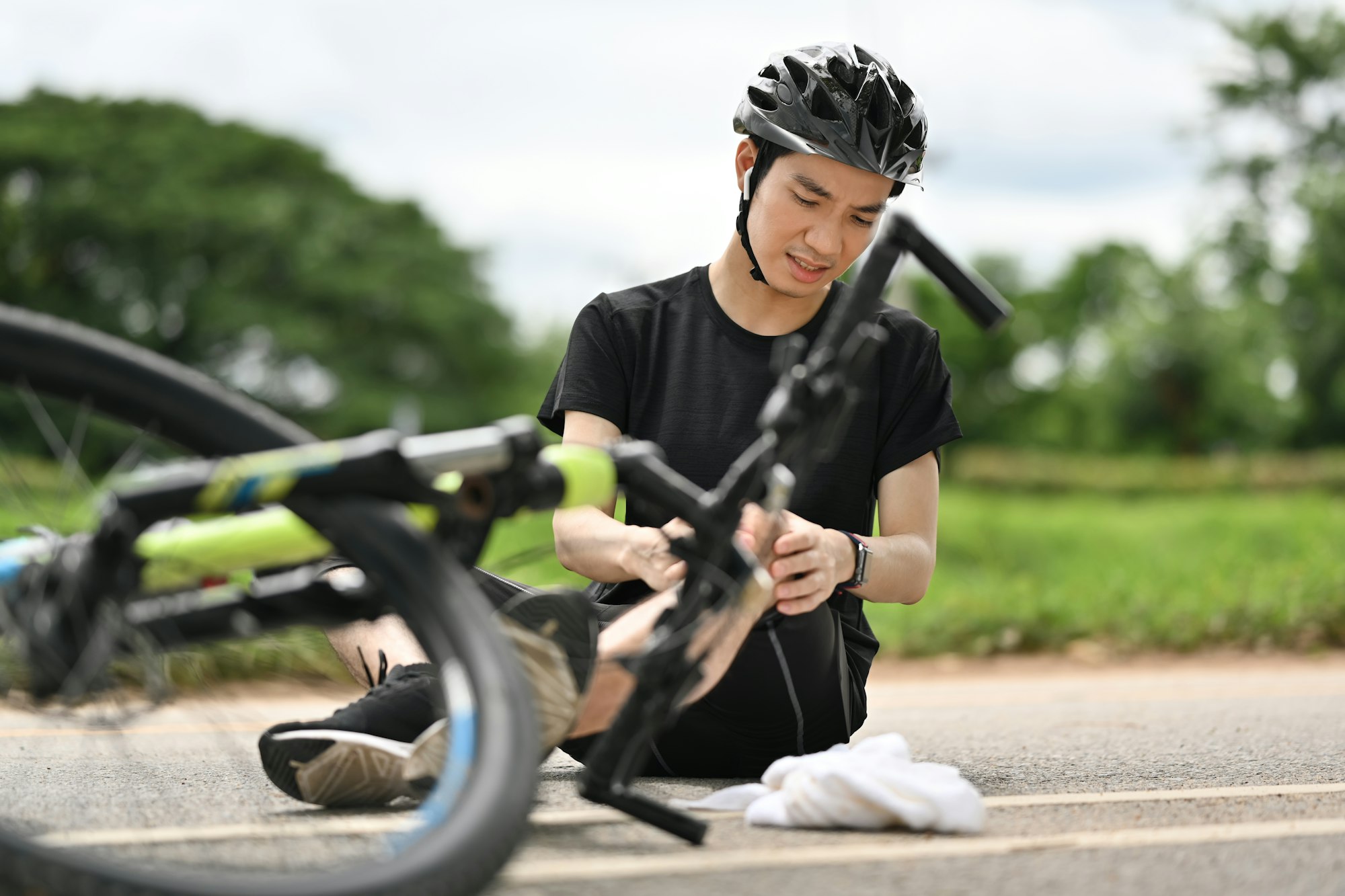 Bicycle accident. Young cyclist having an accident, falling down from bicycle and injured his knee.