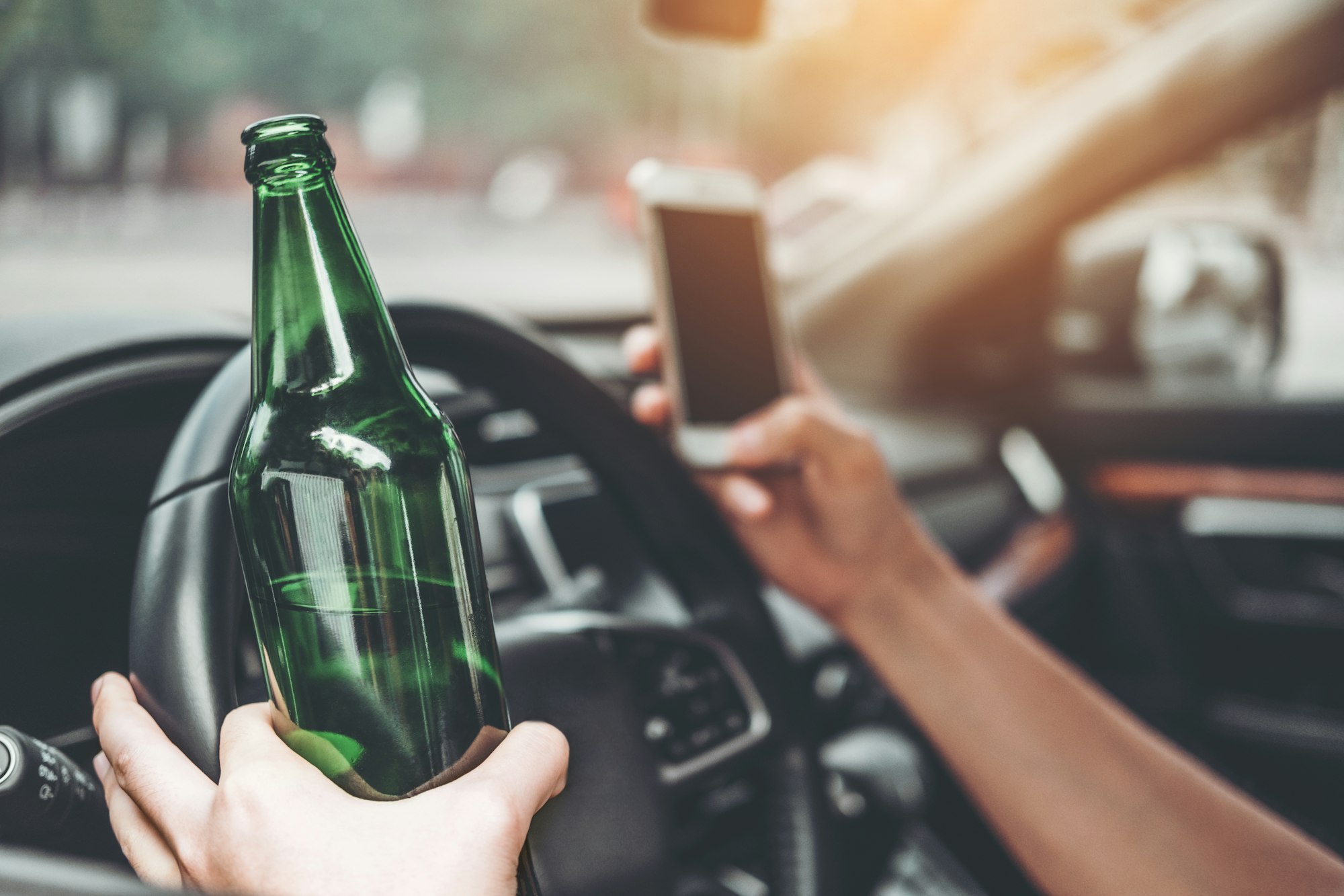 Drunk man driving a car on the road holding bottle beer Dangerous drunk driving concept