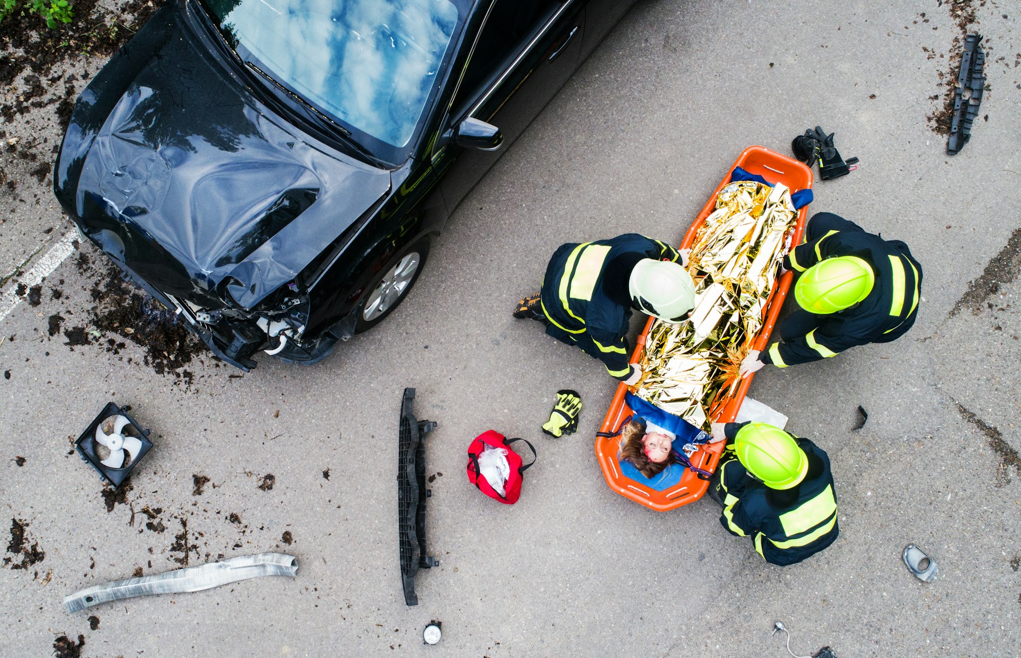 An injured woman in a plastic stretcher after a car accident, covered by thermal blanket.