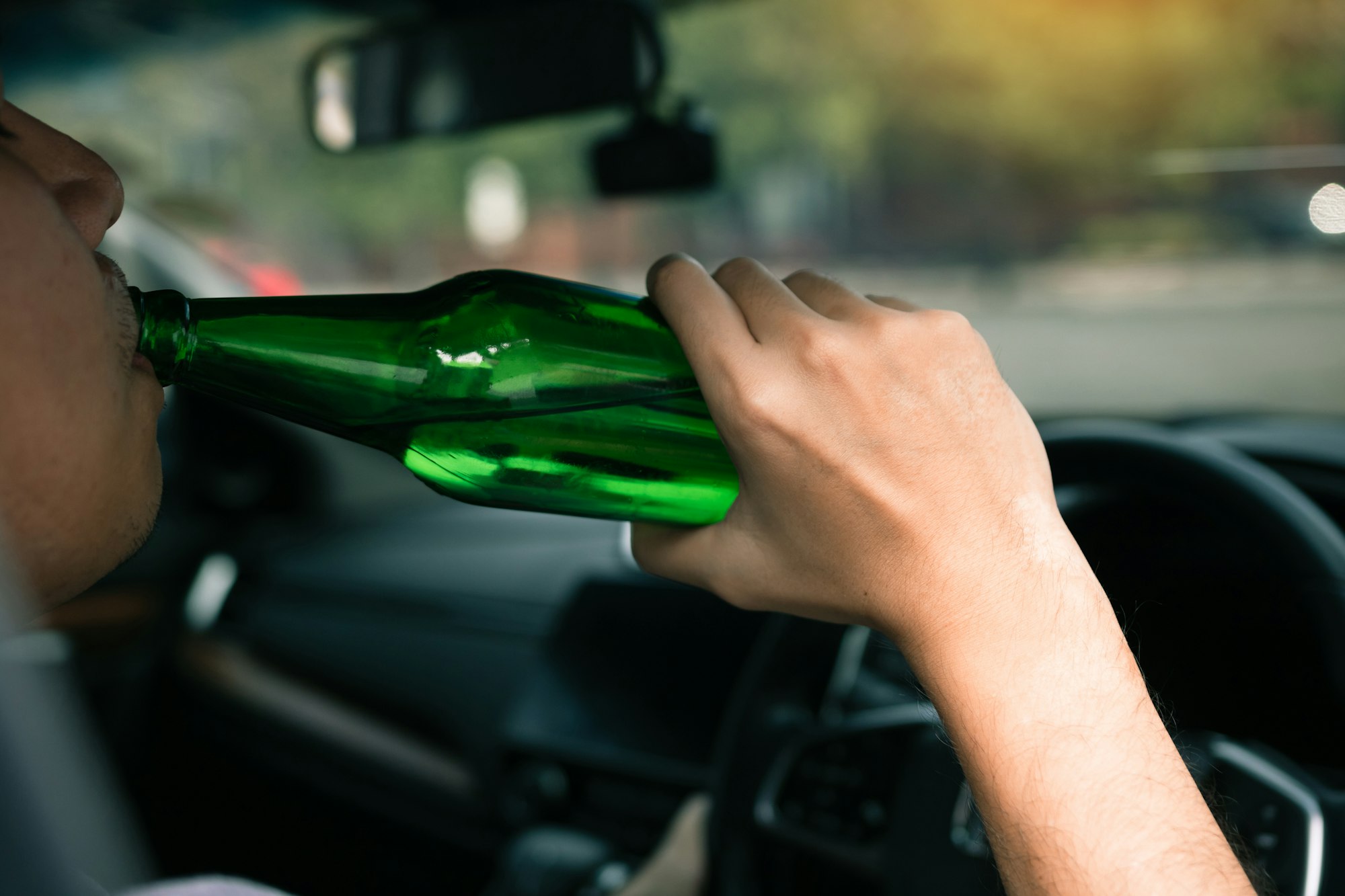 Asian men are breaking the traffic rules by holding a bottle of beer and drinking while driving.