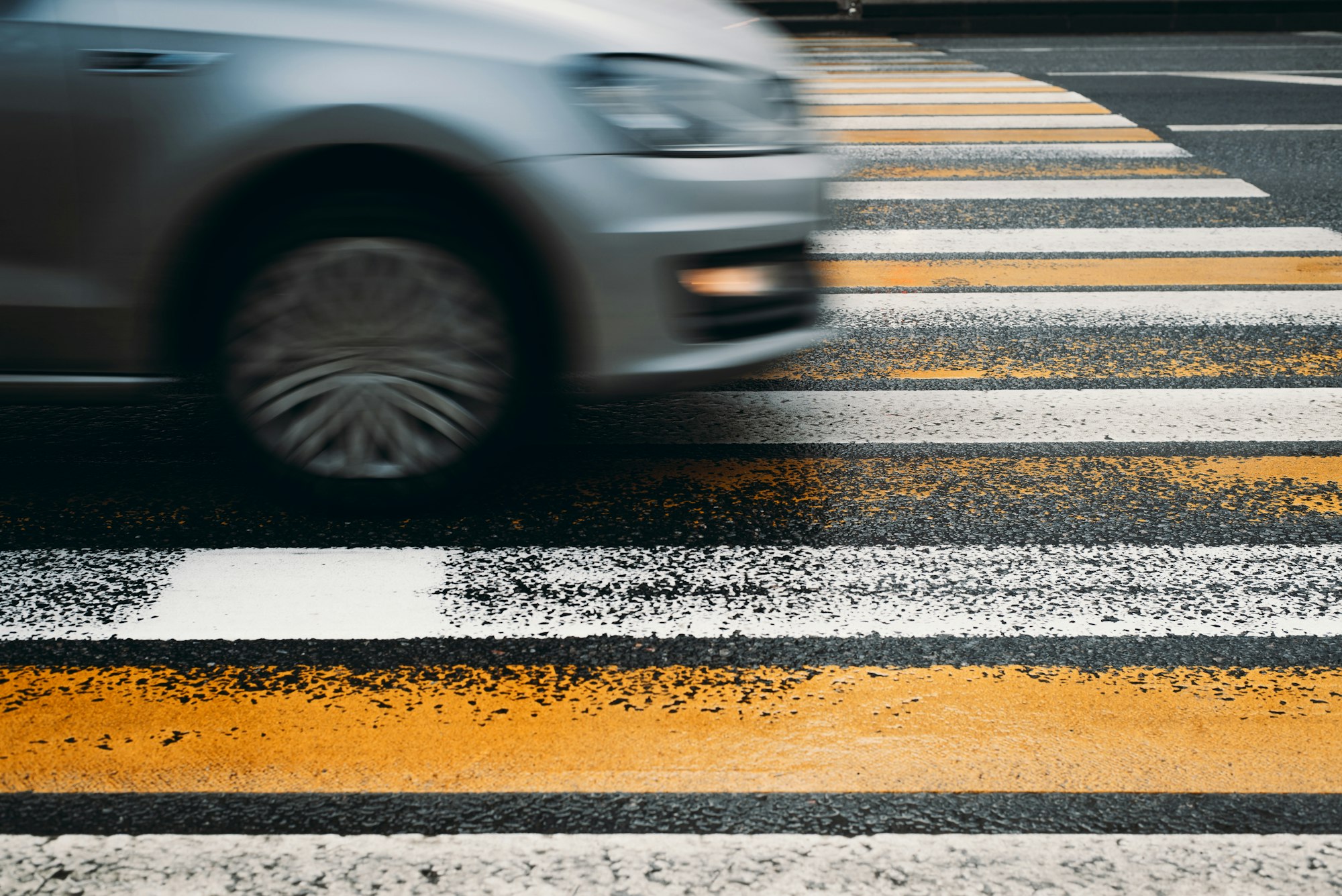 Car driving into a pedestrian crossing. Motion blur, selective focus. Violation of traffic rules