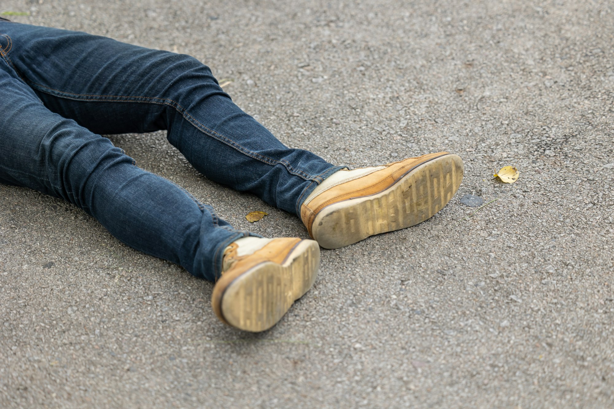 closeup male leg lay down on asphalt road. pedestrian hit accident by car concept.