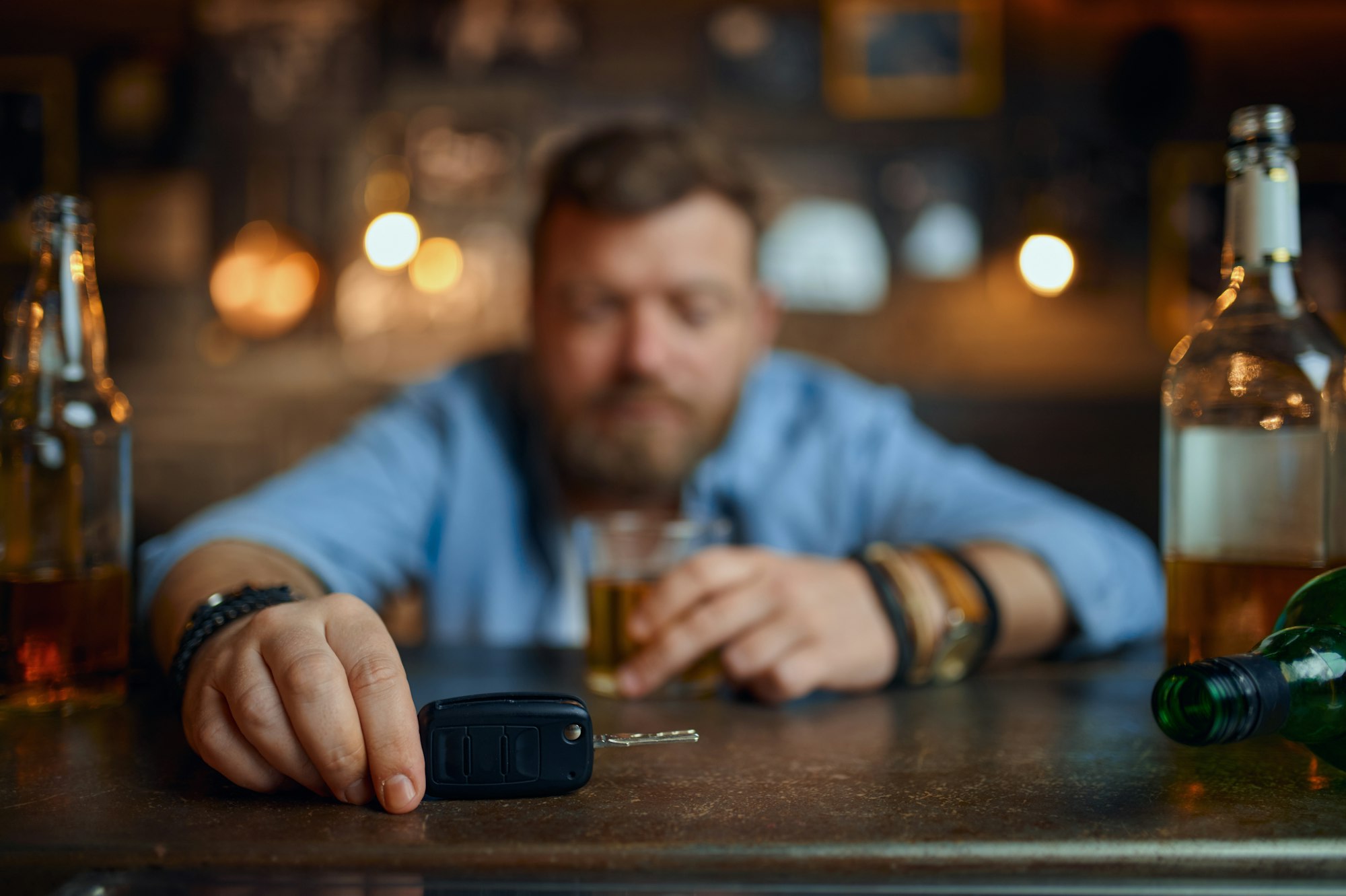 Drunk man with car key sitting at counter in bar