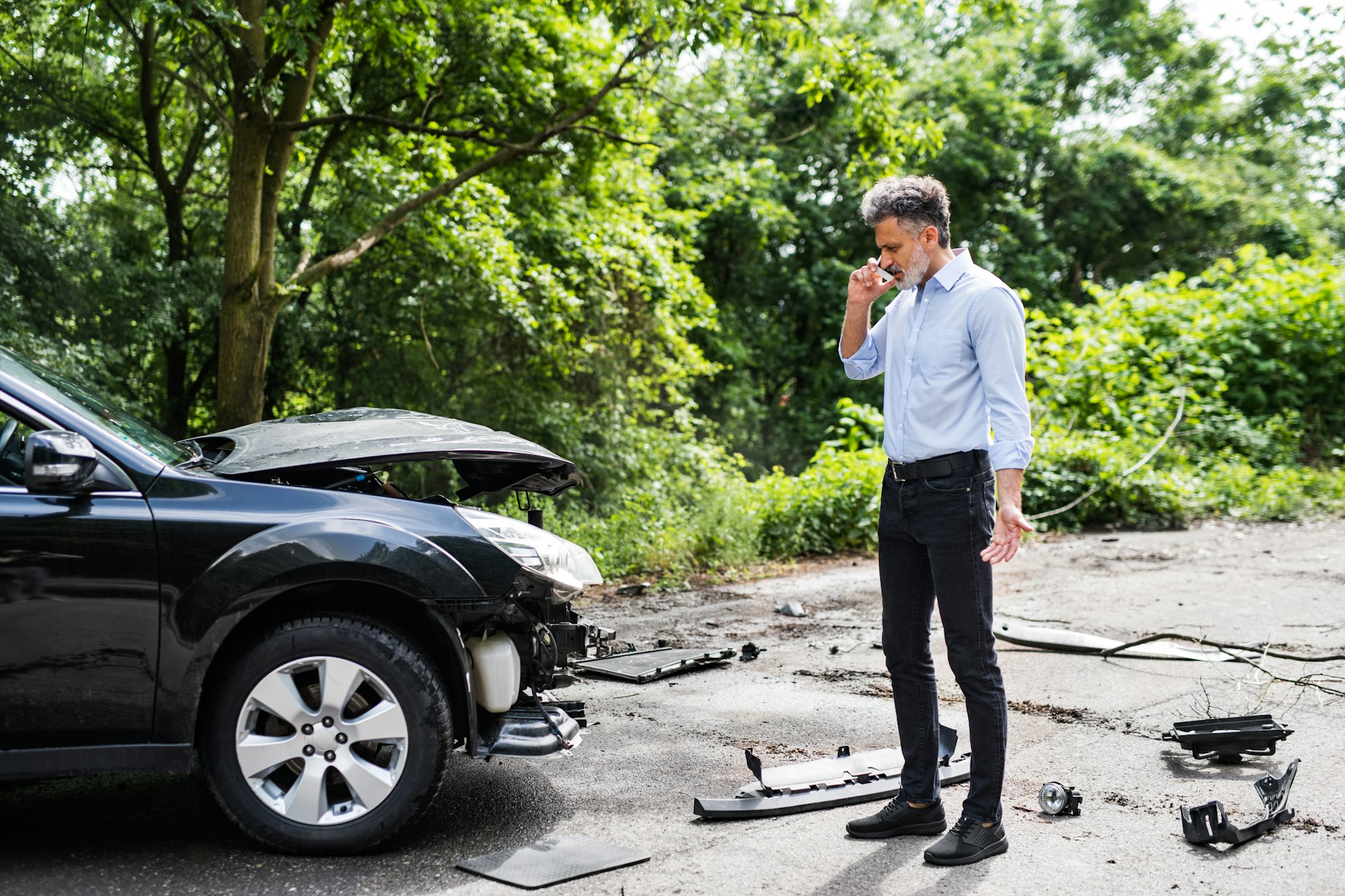 Mature man standing by the car, making a phone call after a car accident.
