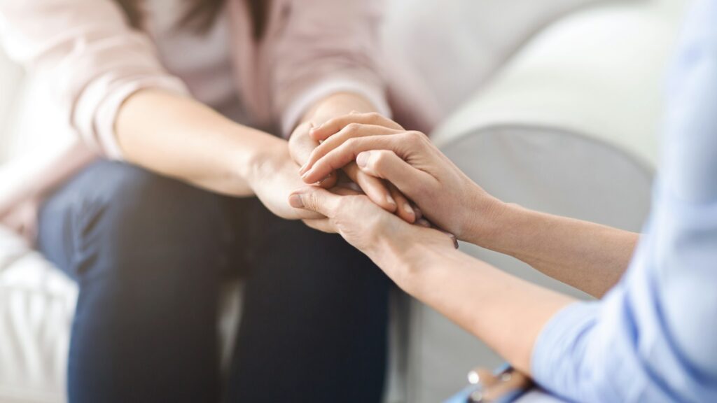 Two Women Offering Emotional Support With Hand Holding