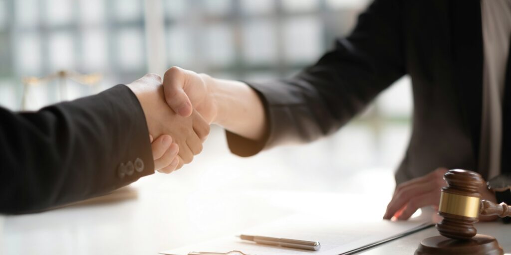 Businessman shaking hands partner lawyers or attorneys discussing a contract agreement.