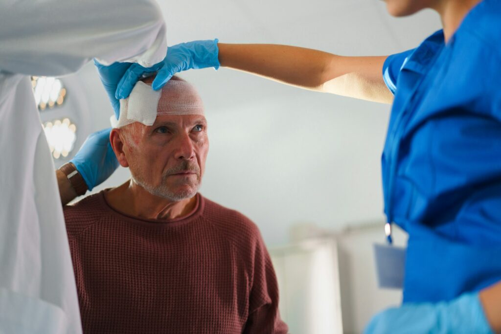 Close-up of doctor and nurse treating injury of senior man.