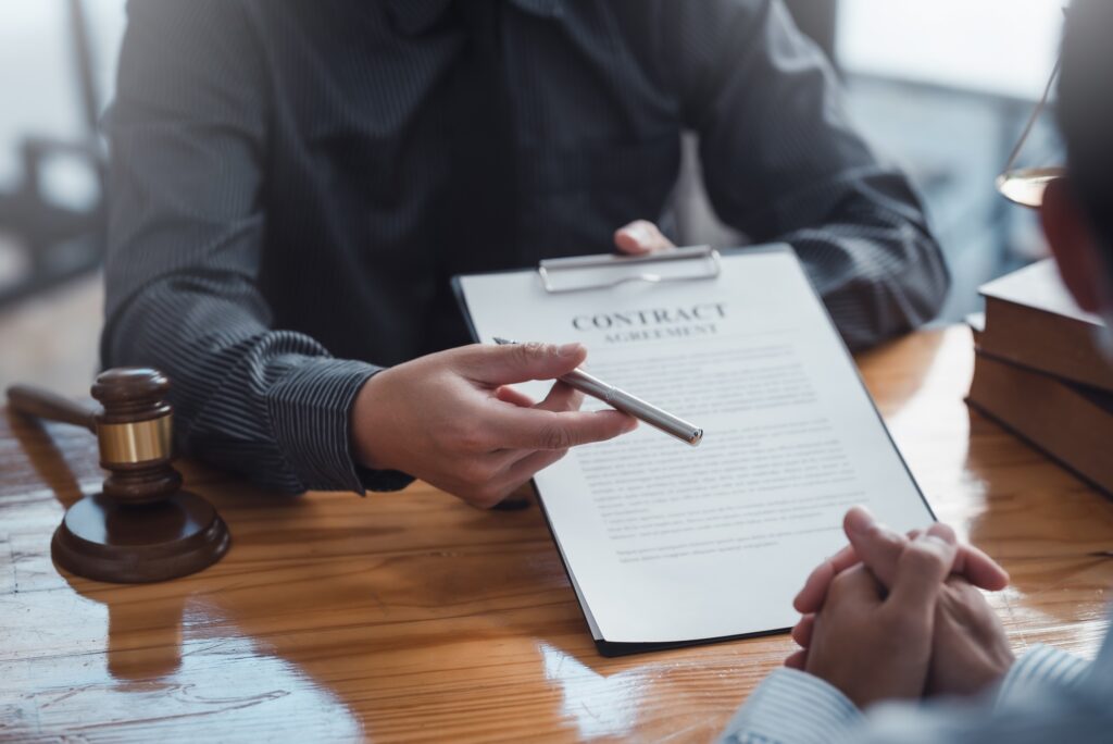 a person holding a pen over a contract