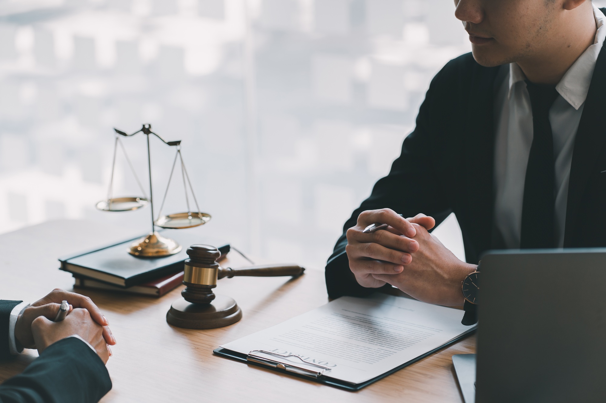 Lawyer working with client discussing contract papers with brass scale about legal legislation in