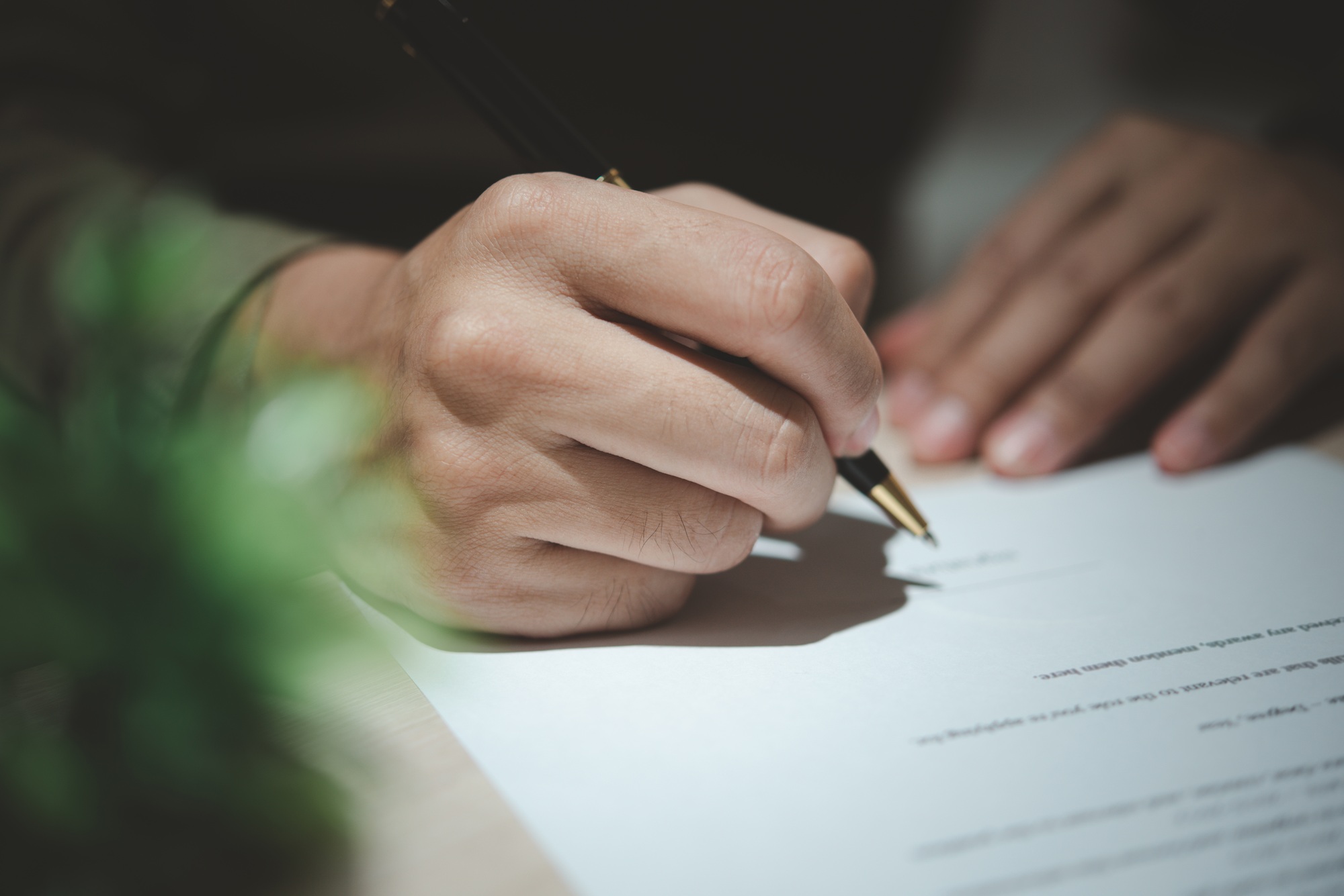Businessman holding a pen signing a document, law ,job search, write a personal contract on desk.