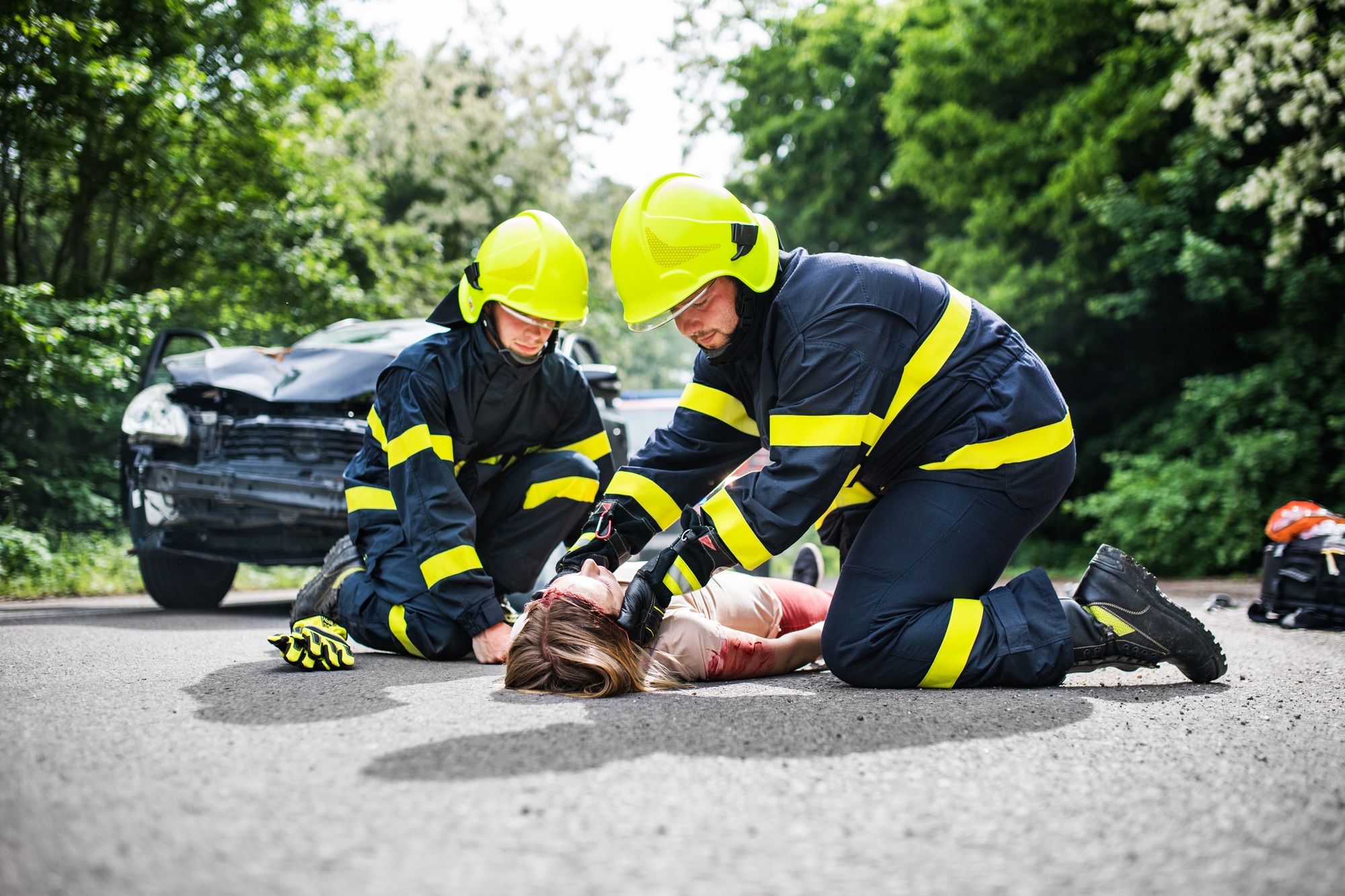 Firefighters helping a young injured woman after a car accident.