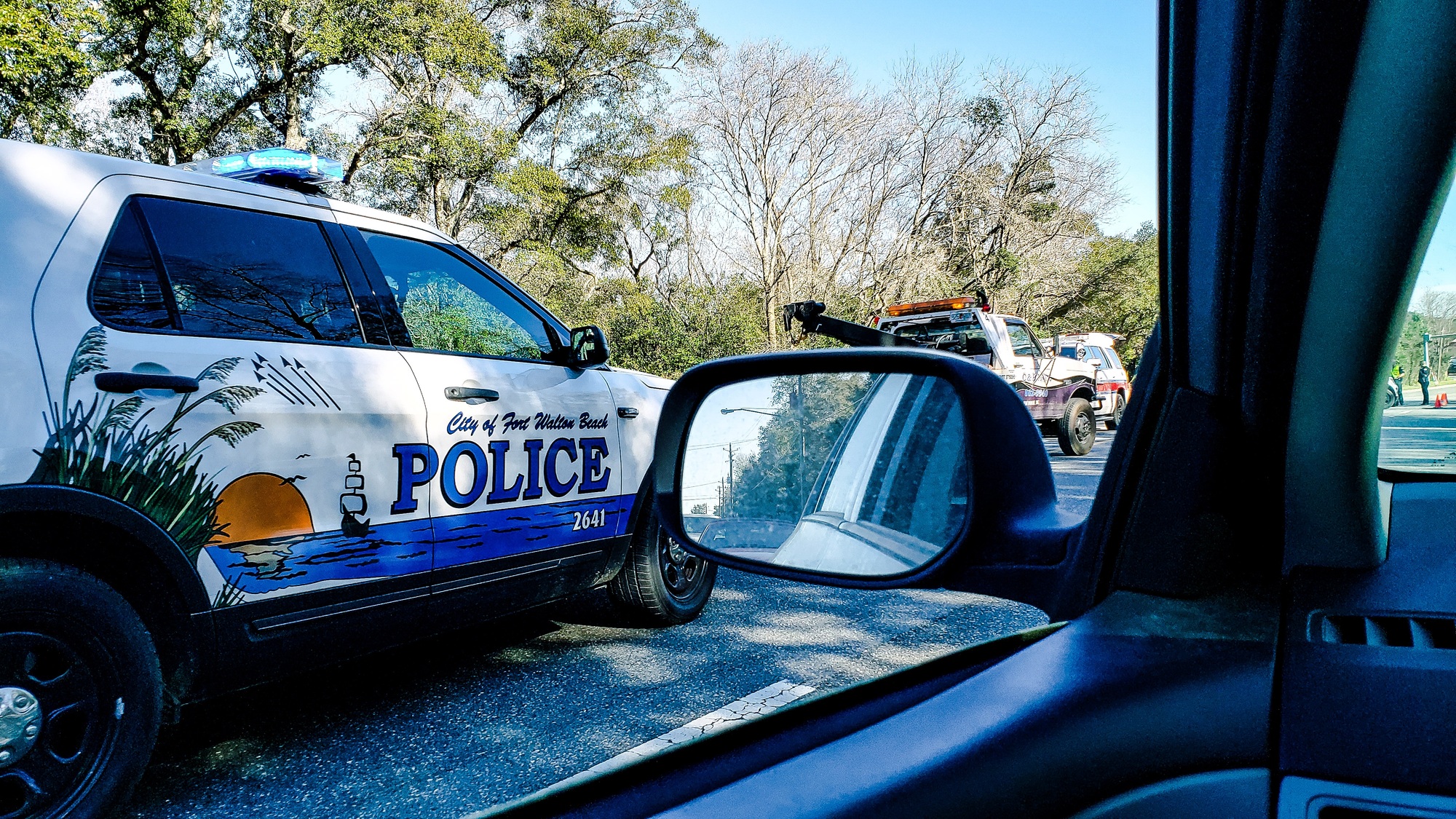 Man driving observes a police car through a window and automatically slows the vehicle.