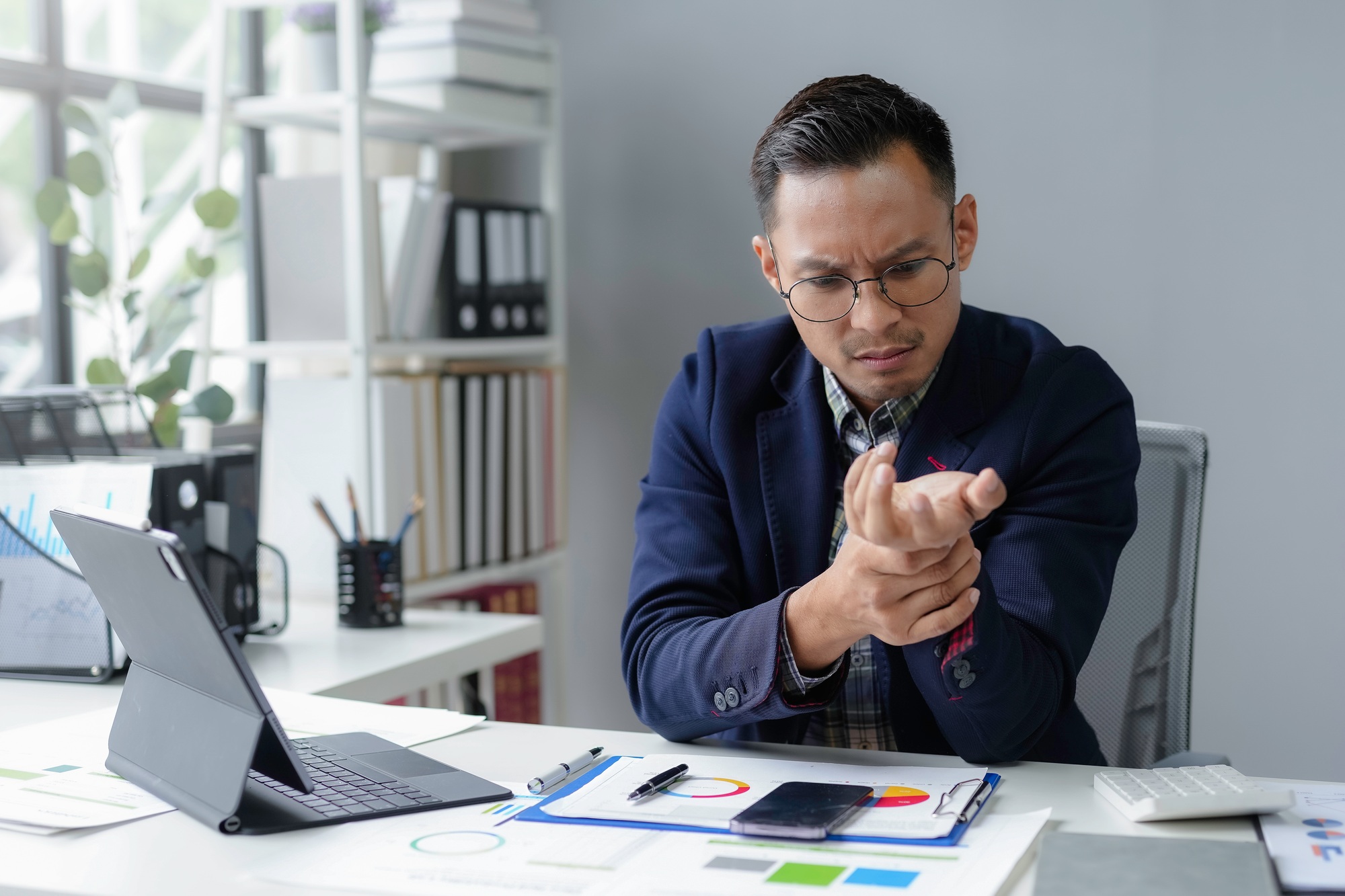Young businessman suffering wrist pain while working in office