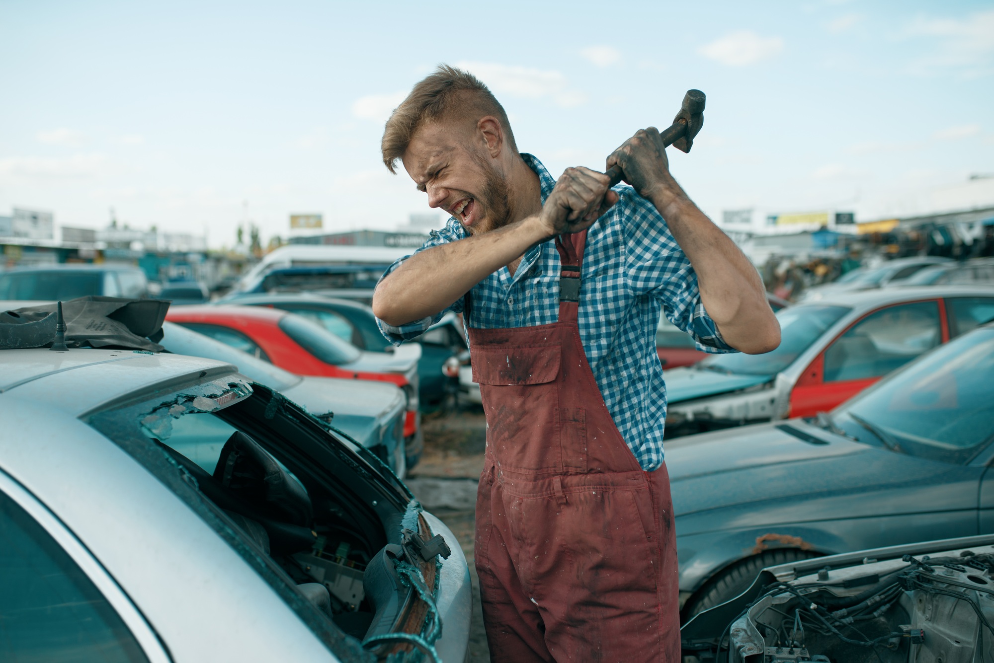 Repairman hits the glass with hammer, car junkyard