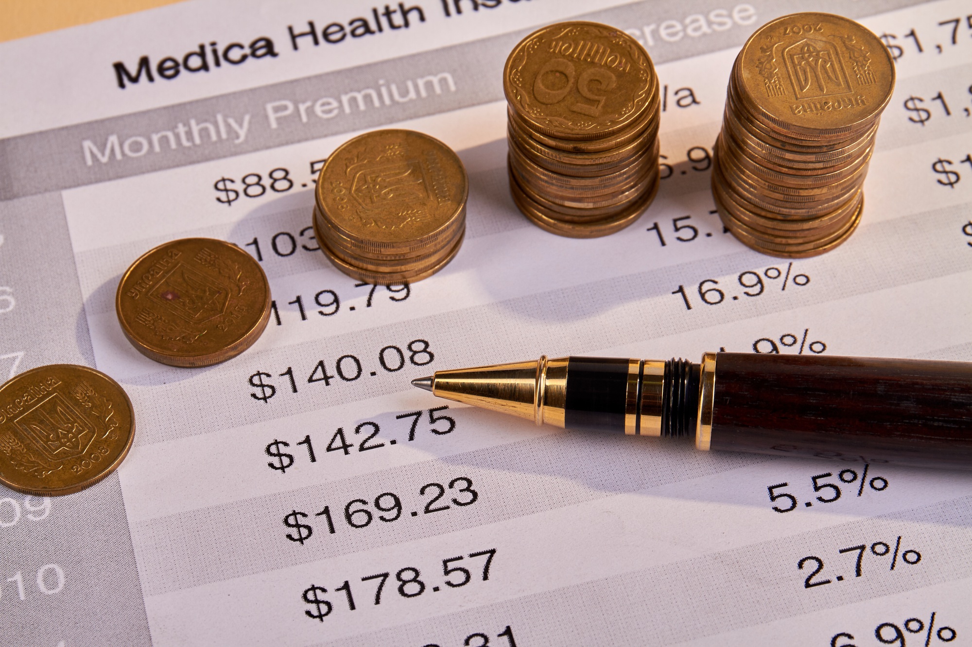 Medical health insurance bill with pen and coins