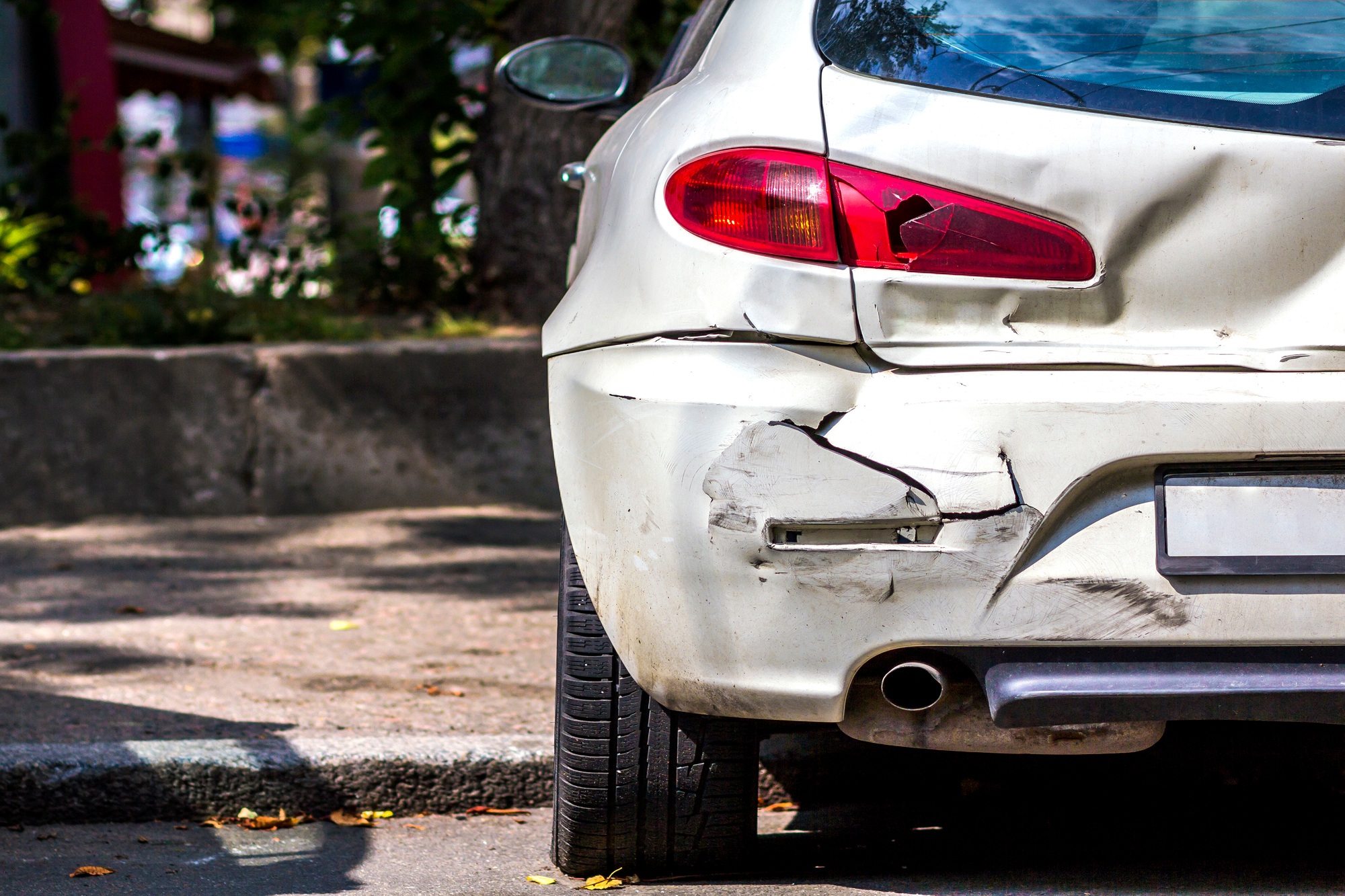 Back of white car damaged by accident on the road
