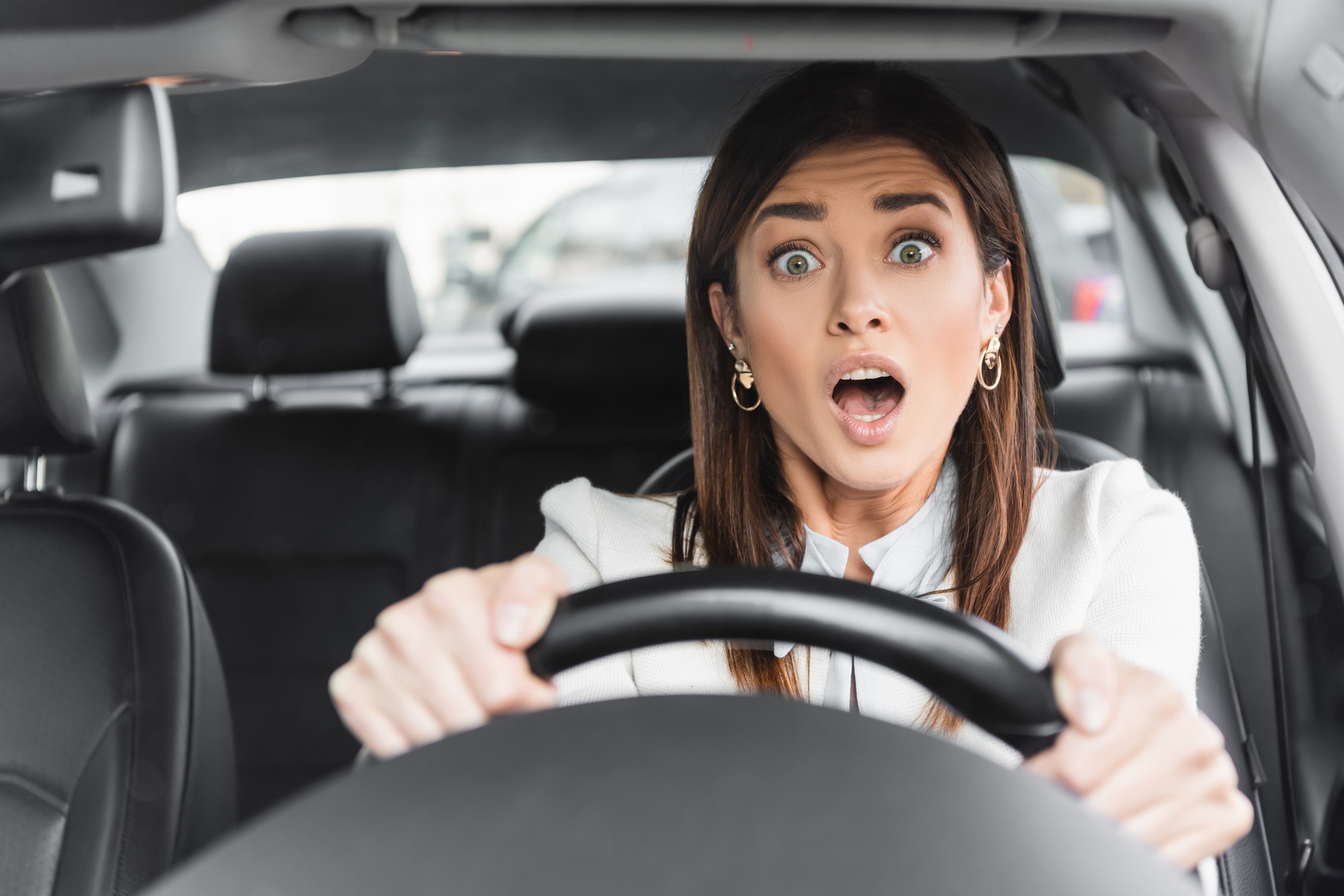 frightened woman screaming while driving car on blurred foreground